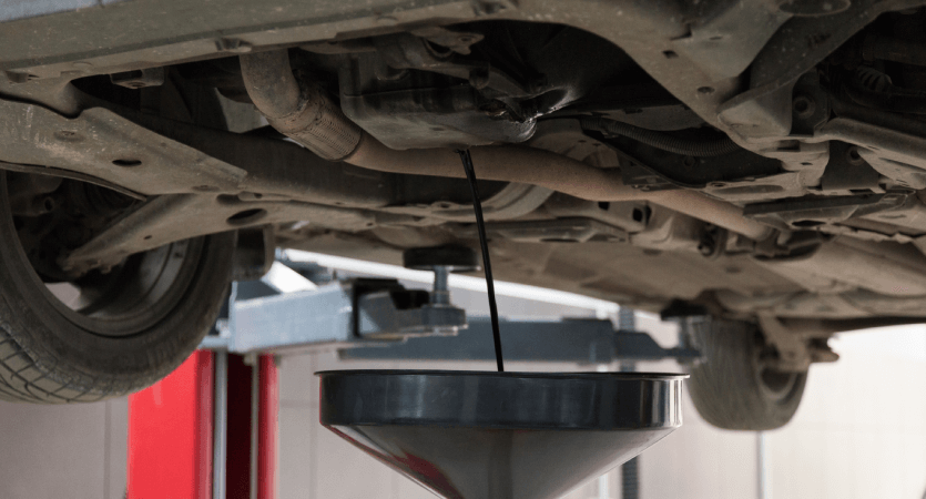 Auto Mechanic Draining Car Oil